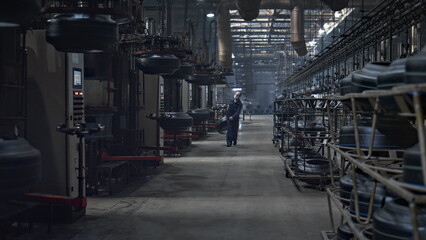 Tire plant storage worker carrying new rubber product in workshop facility