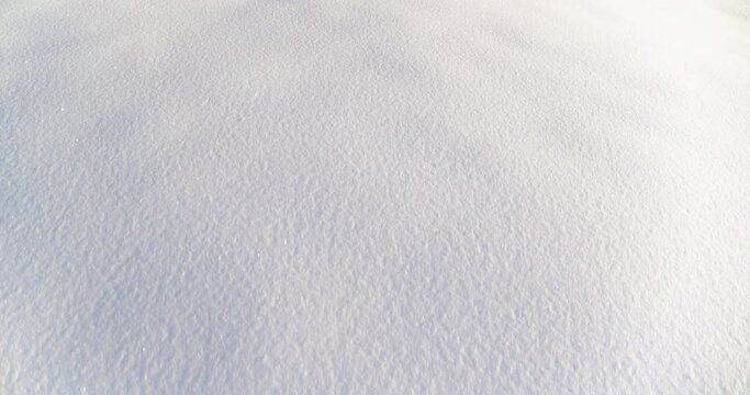 Flying over snow and revealing trees and mountains in the background in winter