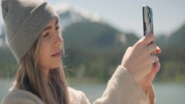 Blonde young woman wearing a beenie takes a picture outside on a cruiseship traveling in Alaska. Medium Close Up. Anamorphic 