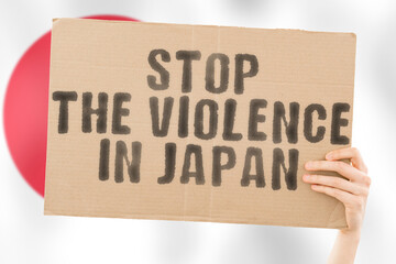 The phrase " Stop the violence in Japan " is on a banner in men's hands with a blurred Japanese flag in the background. Sad. Rights. Security. Social. Stress. Combat. Hate. Cruelty. Furious. Hitting