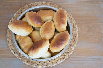 Handmade Russian stile delicious warm pies are cooked in the oven are preparing for weekend breakfast waiting at the wooden structure cruft table in the farm kitchen. No diet day.