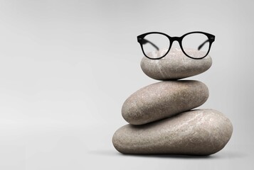 Black glasses on stack stones on gray background. Optic store discount