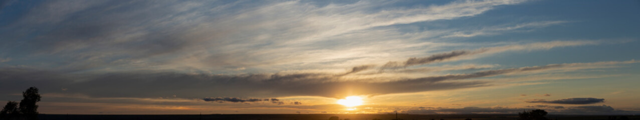 Landscape with bloody sunset. Panorama. Tragic gloomy sky. The last flashes of the sun on the storm clouds.