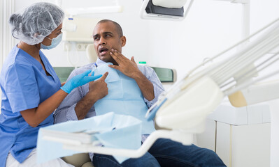 Man in medical chair complains of toothache to dentist