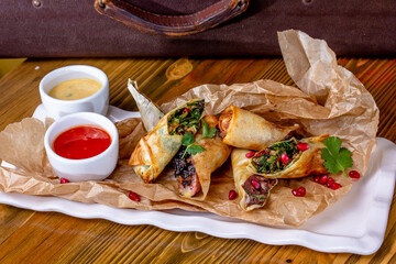 Deep fried spring rolls made it from spring roll pastry,vermicelli,carrots,cabbage,sprouts,soy sauce and peppers served with sweet chilli sauce on slate plate background.Easy vegetarian food.
