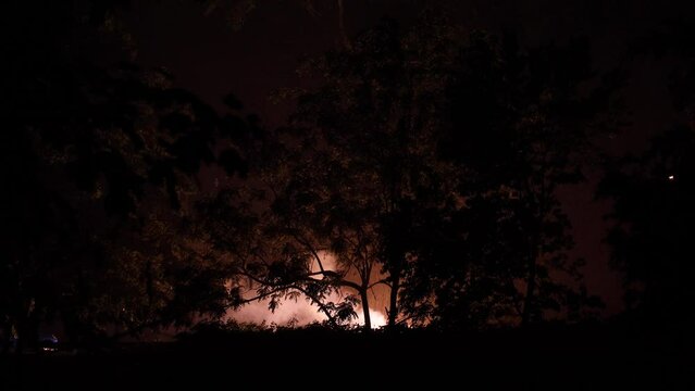 Flashing lights from exploded transformer backlights trees on a cold wet rainy night in New Jersey while smoke cloud rises