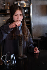 pretty brunette girl making aeropress coffee in modern coffee shop
