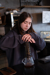 pretty brunette girl making aeropress coffee in modern coffee shop