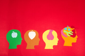 
creative concept four colorful paper heads, in each chapter a paper fruit that represents knowledge the first chapter has the most knowledge, the other heads follow it and learn from it
