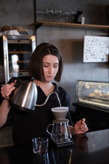 charming brunette woman barista making filter coffee in coffee shop. brewing coffee in cafe