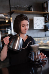 charming brunette woman barista making filter coffee in coffee shop. brewing coffee in cafe