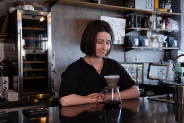 charming brunette woman barista making filter coffee in coffee shop. brewing coffee in cafe
