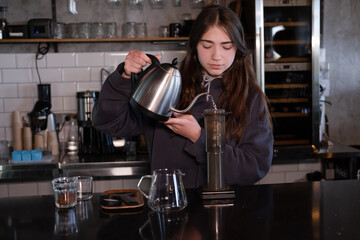 pretty brunette girl making aeropress coffee in modern coffee shop
