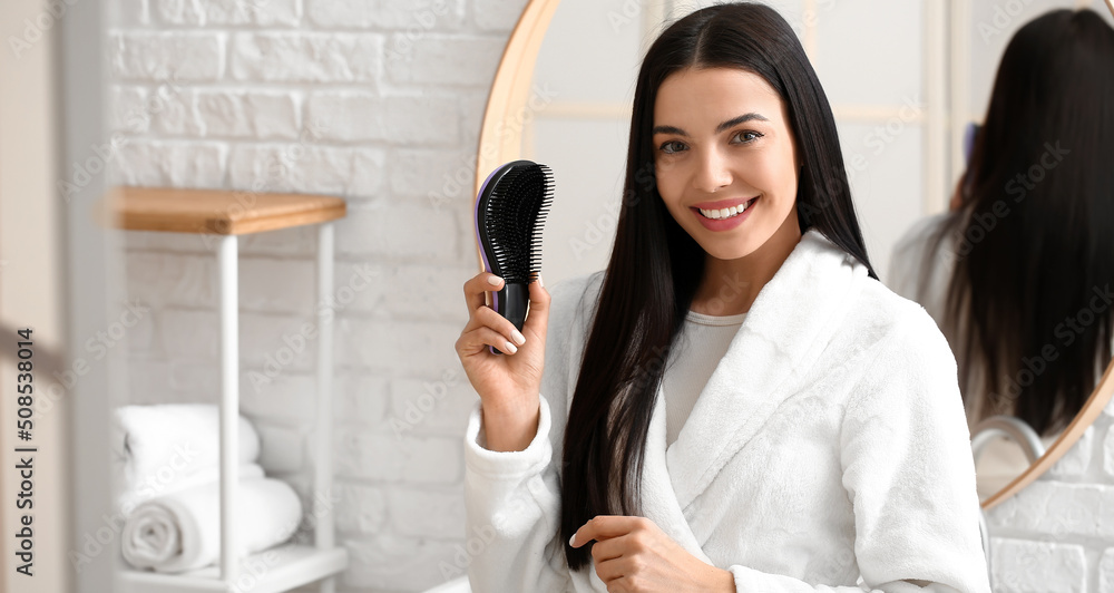 Poster beautiful young woman brushing hair in bathroom