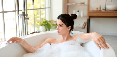 Obraz na płótnie Canvas Pretty young woman taking bath with foam at home