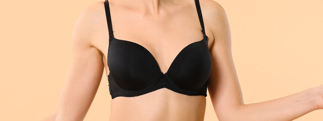 Young woman in black bra on color background