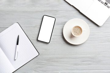 Composition with mobile phone, cup of coffee and notebook on light wooden background