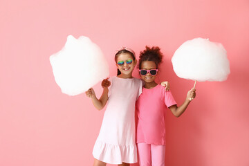 Cute little girls with cotton candy on pink background