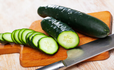 Chopped organic cucumbers on wooden background. Healthy nutrition concept..