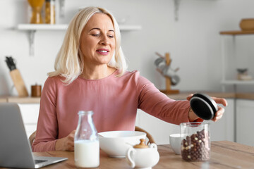 Morning of mature woman having breakfast in kitchen