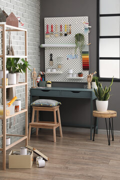 Modern decorator's workplace with different tools near grey brick wall in room interior