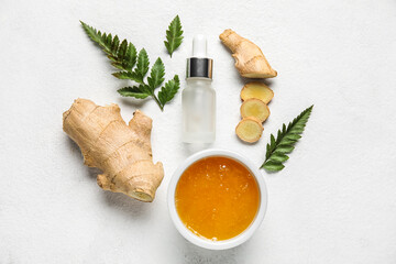 Bottle of natural serum with honey, ginger and fern leaves on white background