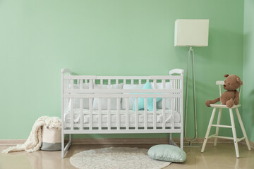 Interior of stylish nursery with baby crib, lamp and chair