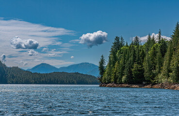 Ketchikan, Alaska, USA - July 17, 2011: Blue cloudscape above landscape of green forests on island...