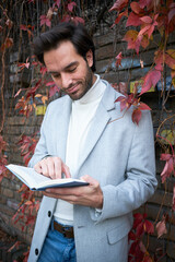 Young handsome businessman enjoying his free time outside on a beautiful autumn day, reading his book