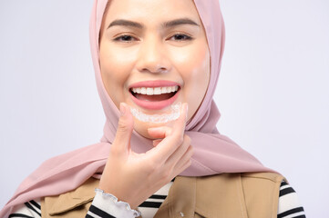 A young muslim woman holding invisalign braces in studio, dental healthcare and Orthodontic concept..