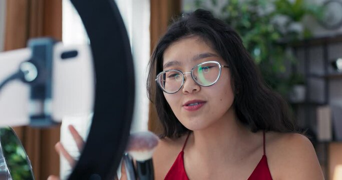 A beginner makes a video on social media with the help of a ring light and phone. Popular makeup artist show off favorite brushes for foundation, bronzer, girl shows off soft bristles.