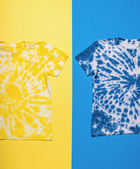 Blue and yellow tie dye T-shirts on a blue and yellow background. Flat lay.