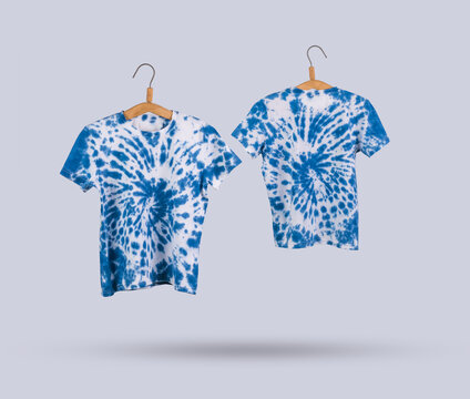 Two blue tie dye T-shirts on hangers on a light background.