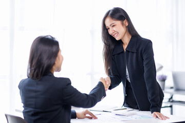 Pretty Young Asian business woman shaking hands with business in her office during a meeting