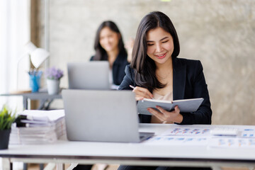 Portrait of Asian office employee businesswoman working in an office, doing planning analyzing the financial report, business plan investment, finance analysis concept. Office background. - obrazy, fototapety, plakaty