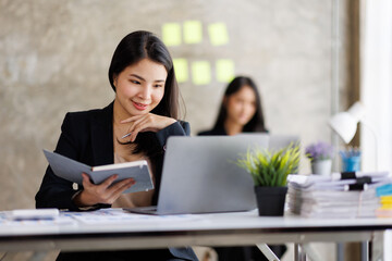 Portrait of Asian office employee businesswoman working in an office, doing planning analyzing the financial report, business plan investment, finance analysis concept. Office background.