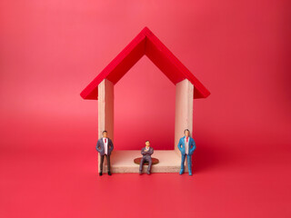 Toy house with miniature people on a red background. Business concept.