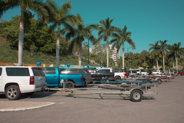 boat trailer truck parking full of vehicles on a summer day with no people, palm trees in the...