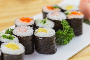 maki sushi set in a white plate placed on a wooden floor