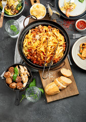 Assortment of Italian pasta with traditional sauces for dinner on dark background. Homemade food concept