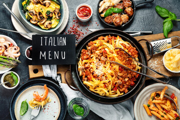 Assortment of Italian pasta with traditional sauces for dinner on dark background. Homemade food concept