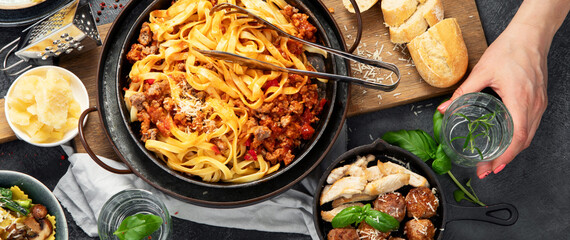 Assortment of Italian pasta with traditional sauces for dinner on dark background. Homemade food concept