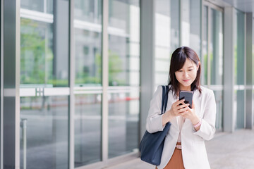 Obraz premium スマホを確認する若いビジネスウーマン