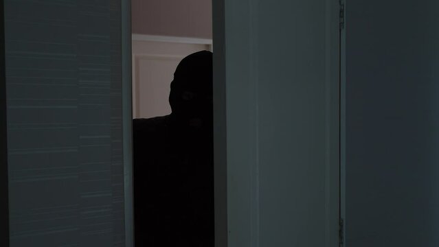 Unrecognizable Man Wearing Balaclava Face Mask Walking Through The Room. Keep your home secure during your summer holiday Concept.