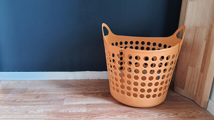 Empty and broken plastic laundry basket orange colored indoors.