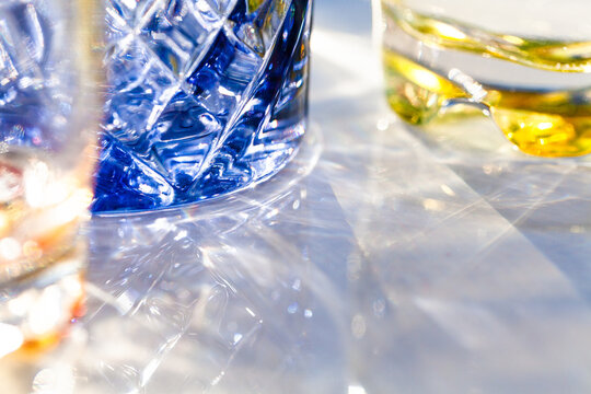 Light through collection of colourful water glasses in sunlight