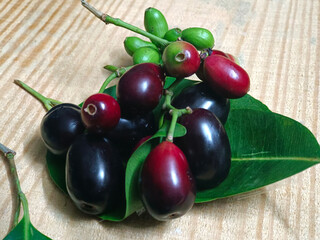 Fresh Jambolan plum or Java plum (Syzygium cumini) with leaf on wooden table.