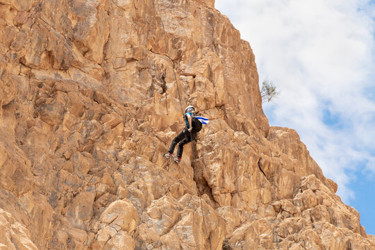 Experienced athlete on Israel Independence Day descending with equipment for rappel in mountains of Judean Desert, near Khatsatson stream, near Jerusalem, Israel.