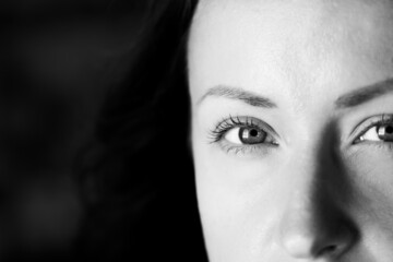 Black and white photograph of an attractive woman. A large portrait on a dark background. Macro photo, top of the face. Front view.
