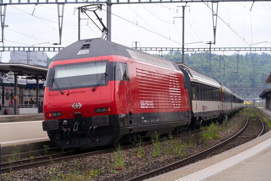 SBB train with red locomotive at railway station of Brugg, Canton Aargau, on a cloudy spring day. Photo taken May 6th, 2022, Brugg, Switzerland.